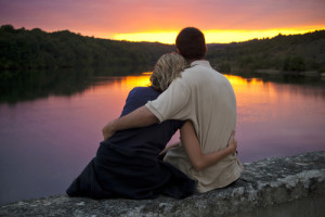 A couple gently embrace as the sun sets